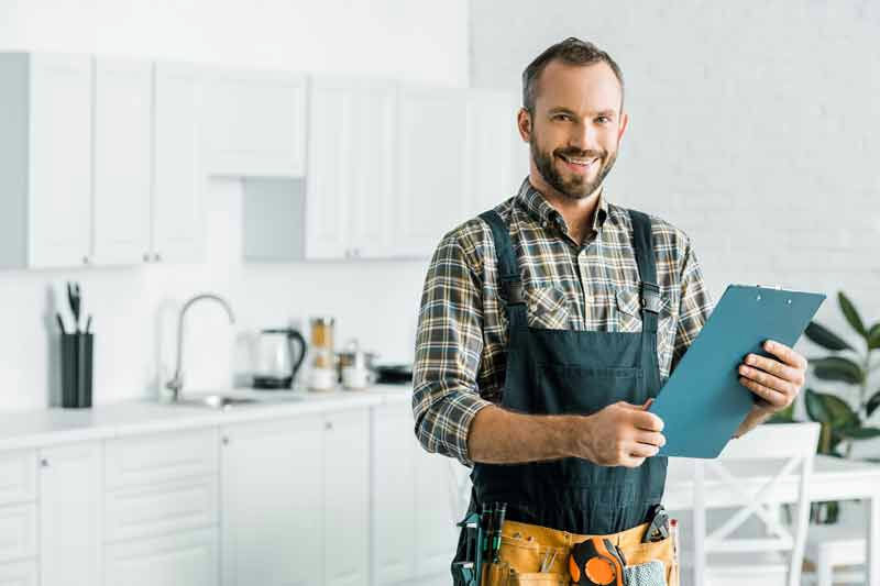 a handyman standing in a kitchen holding a clip board