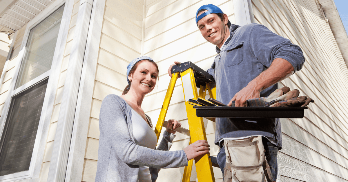 a man and woman standing on a ladder outside their home ready to make some home repairs. the man is holding tools