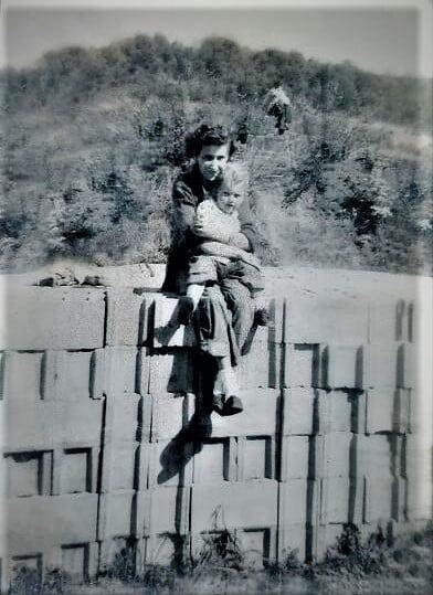 black and white photo of a woman siting on cinder blocks holding a toddler
