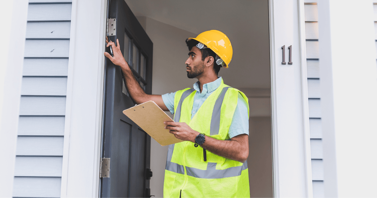 a handyman checking the weatherstripping on an exterior door of a home