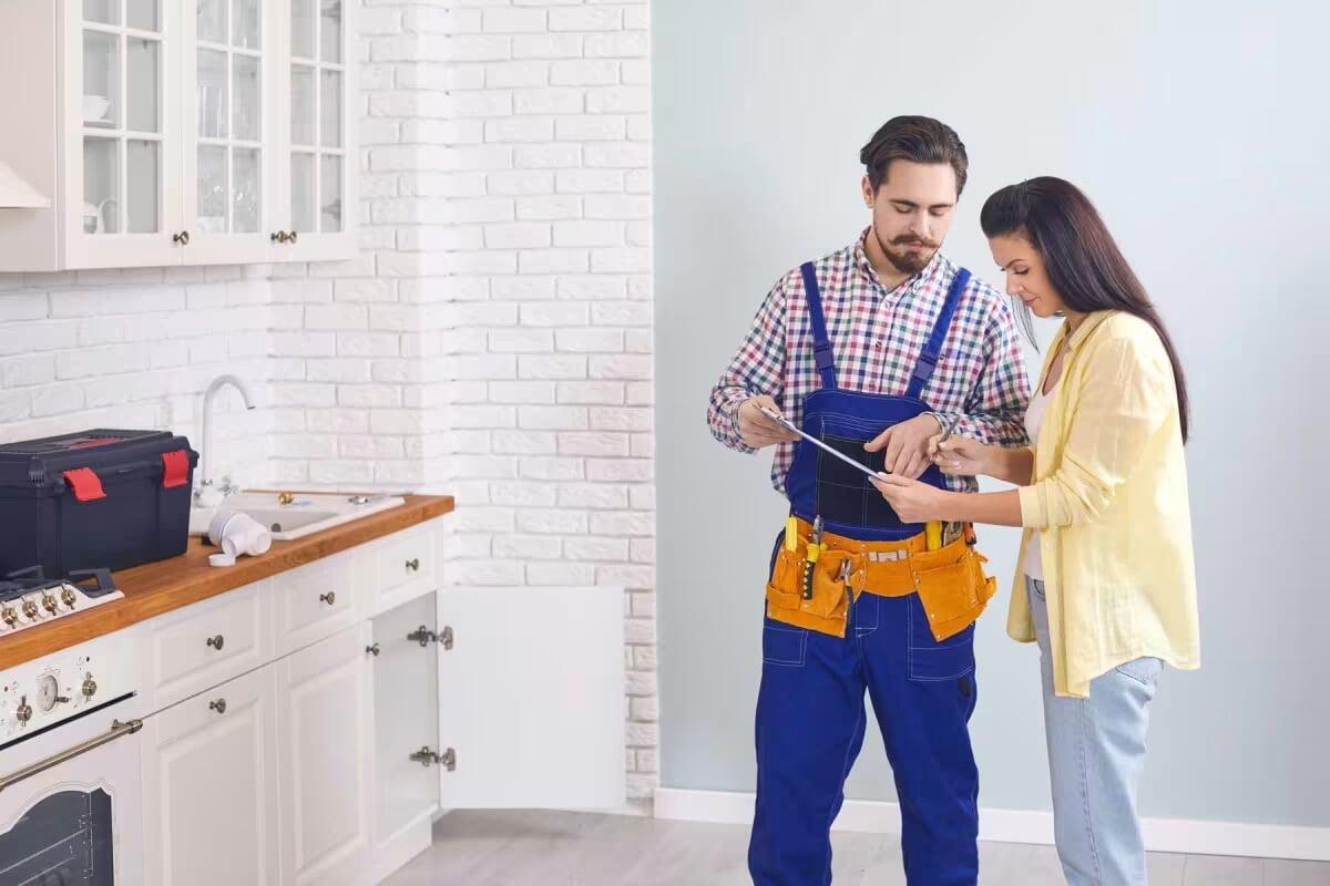 a handyman talking to a woman in her kitchen about a household repair